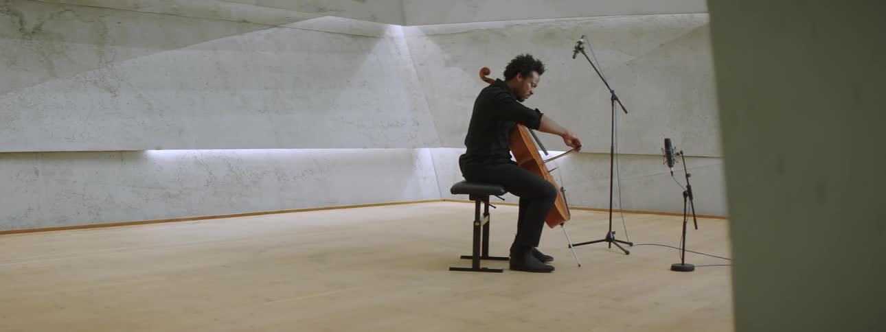 An inspired musician playing cello on a stage in front of microphones