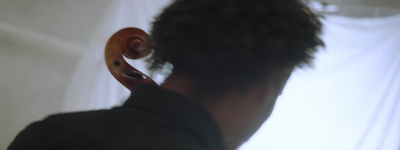 A man playing the cello in an auditorium