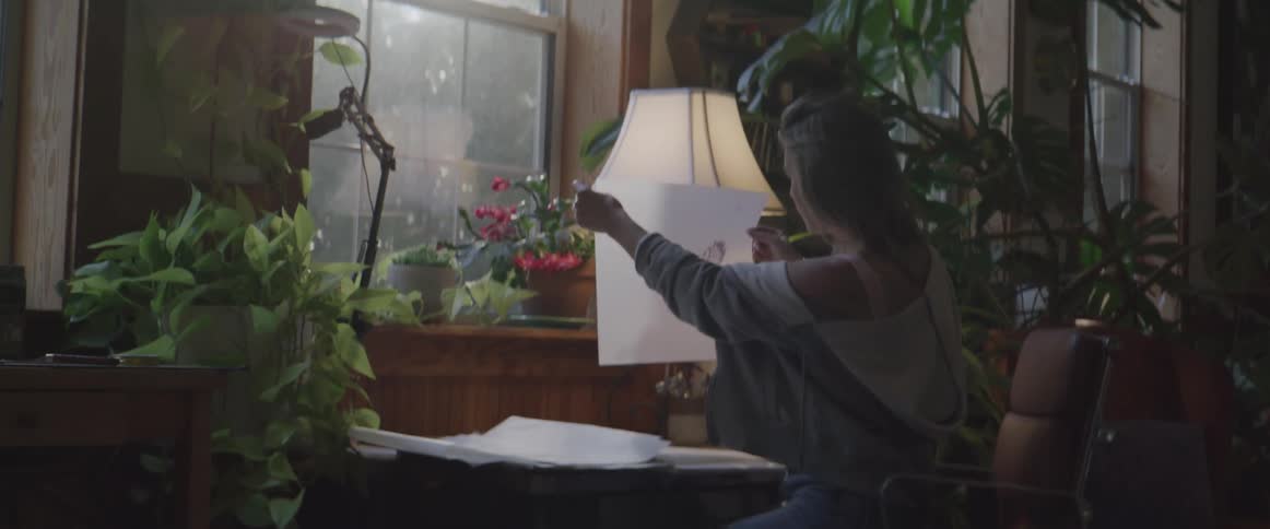 A woman seating close to a window sorting out different sheet of papers
