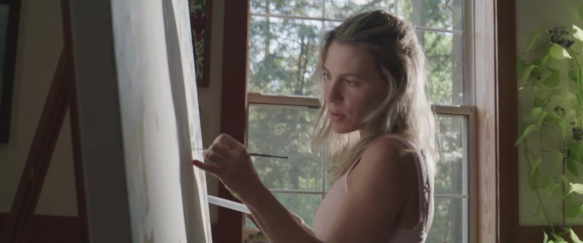 Female artist standing in studio paints large canvas
