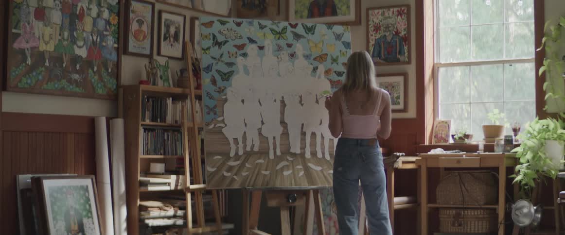Woman inside a room painting a picture while dancing