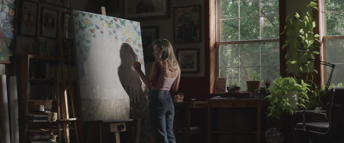 A woman is painting on a large easel