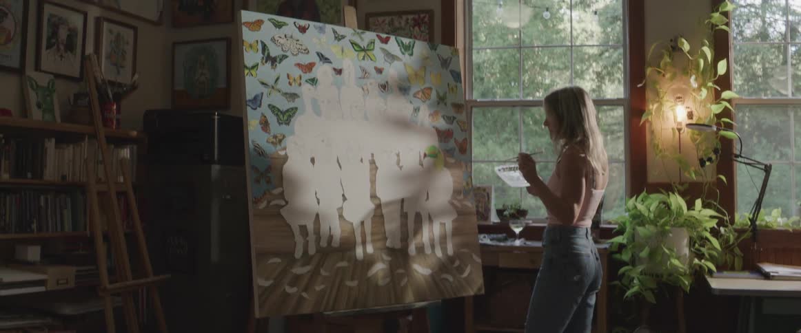 A happy woman dancing while painting a canvas
