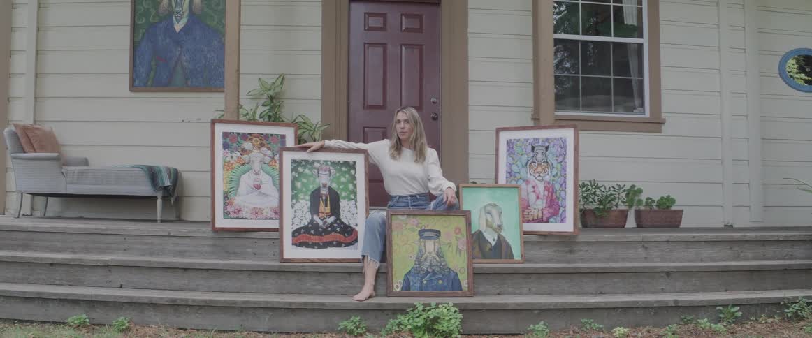 A woman sitting outdoors with her paintings