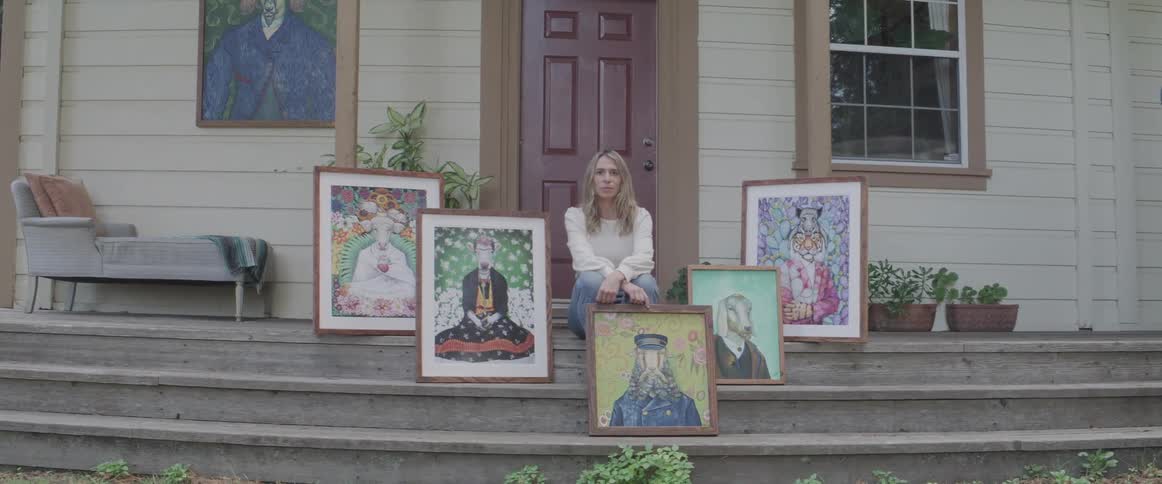 A woman sitting on the stairs at home with art canvases