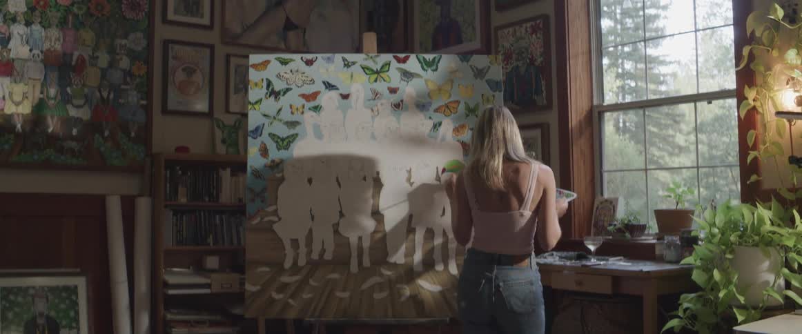 Woman inside a room painting a picture while dancing