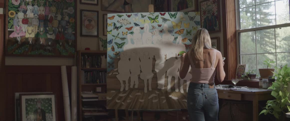 A white woman paints on a large canvas