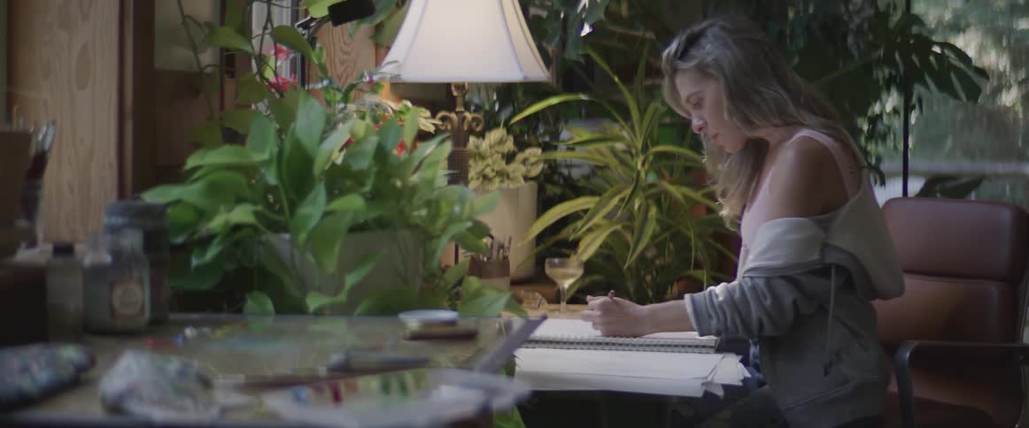 Young man and woman sitting in a room at a desk writing
