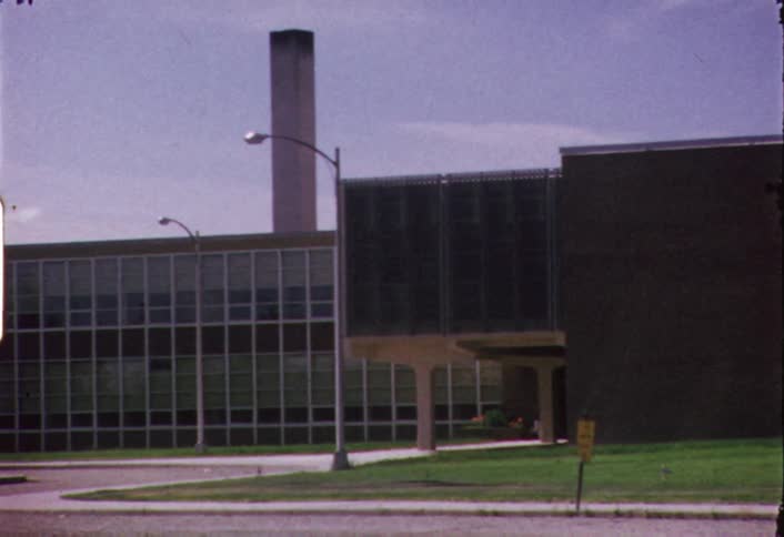 A vehicle passes by an office building during the day