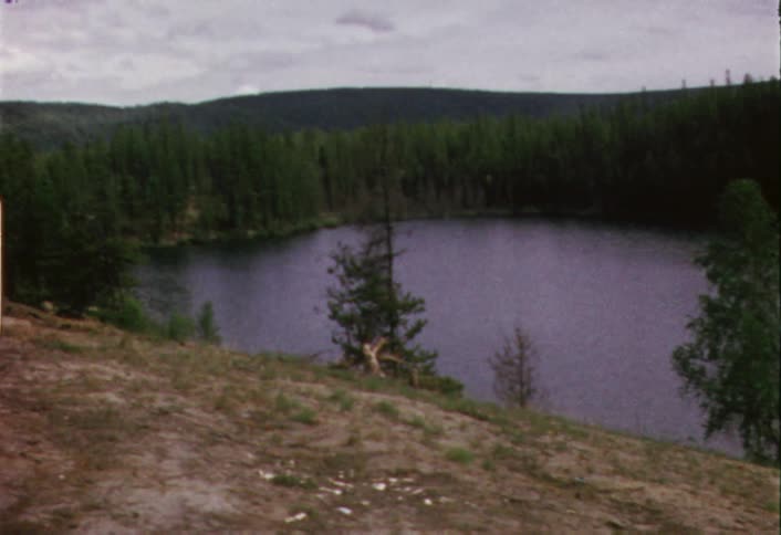 Calm lake surrounded by trees on the far side on a cloudy day