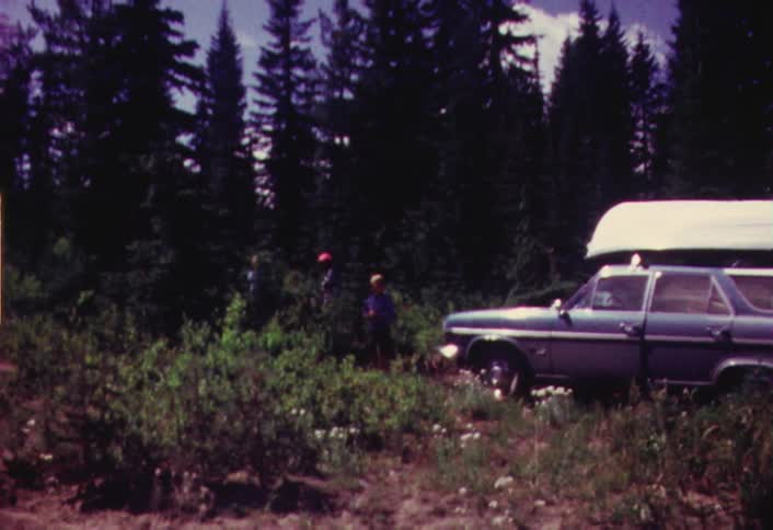 Group of people in the wilderness with their car and a small boat on top of it