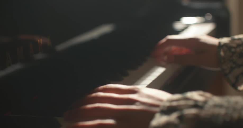 Close in the hands of a woman playing the piano