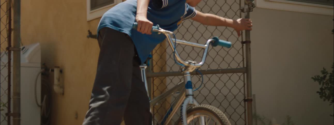 Teenager getting on his bike and leaving through the gate
