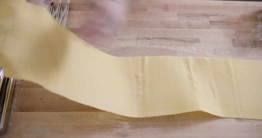 A man unfolds a piece of uncooked pasta that he will cut