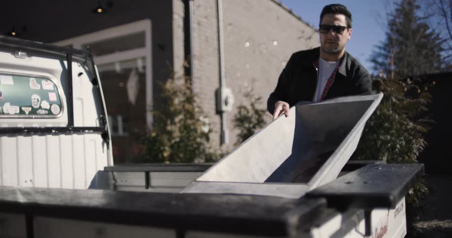 A man arranging items in the back of his pickup truck