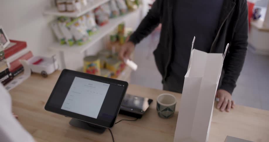 Cashier bags customers items then the customer departs after paying