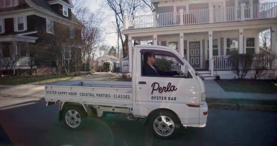 Man driving a small truck through a residential neighborhood