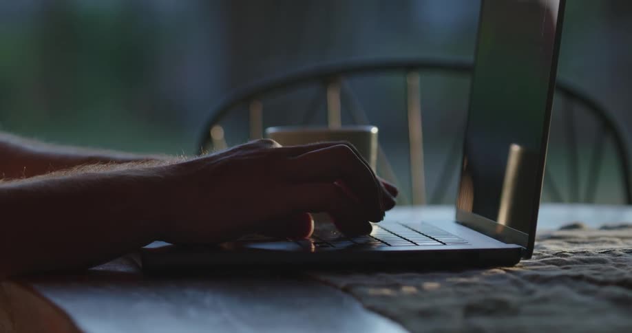 Closeup of a persons hands typing on the laptop on the table
