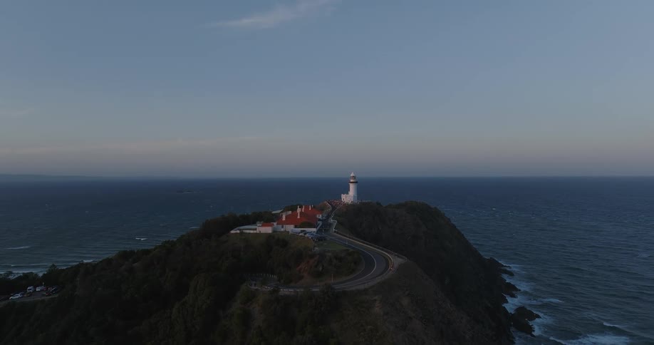 Curving road descends from facility near lighthouse on promontory