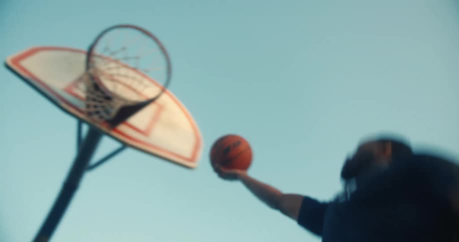 Man on a court jumping and making a basketball hoop