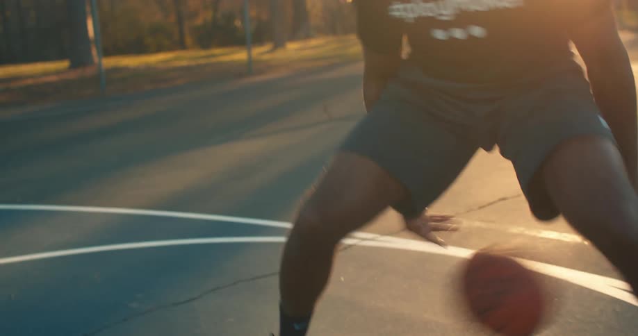A man practicing basketball on a park at morning