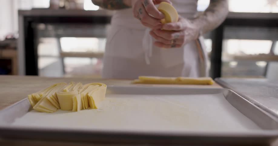 A person arranging pasta dough on a tray