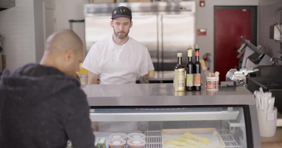 Chef in a restaurant presenting food to a customer at the counter