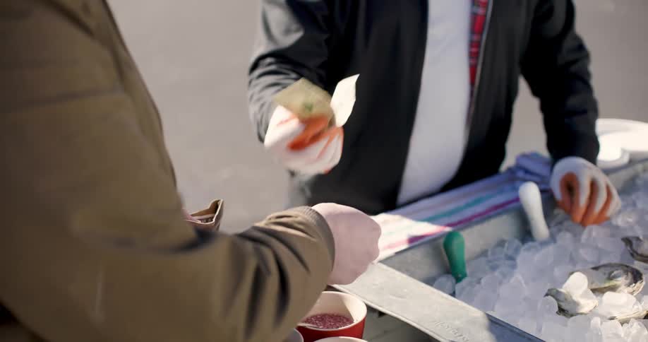 Man took money out of his wallet and gave it to the man at the food stand on a sunny day