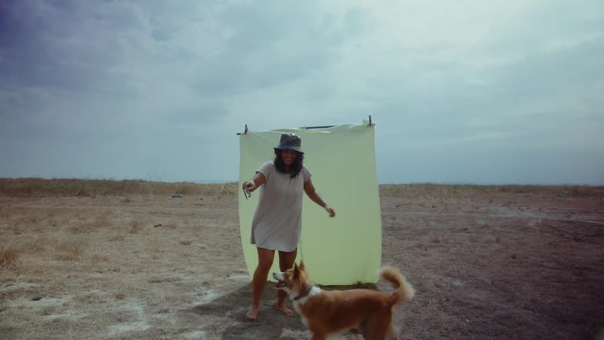Woman plays with her dog in arid field in the Philippines