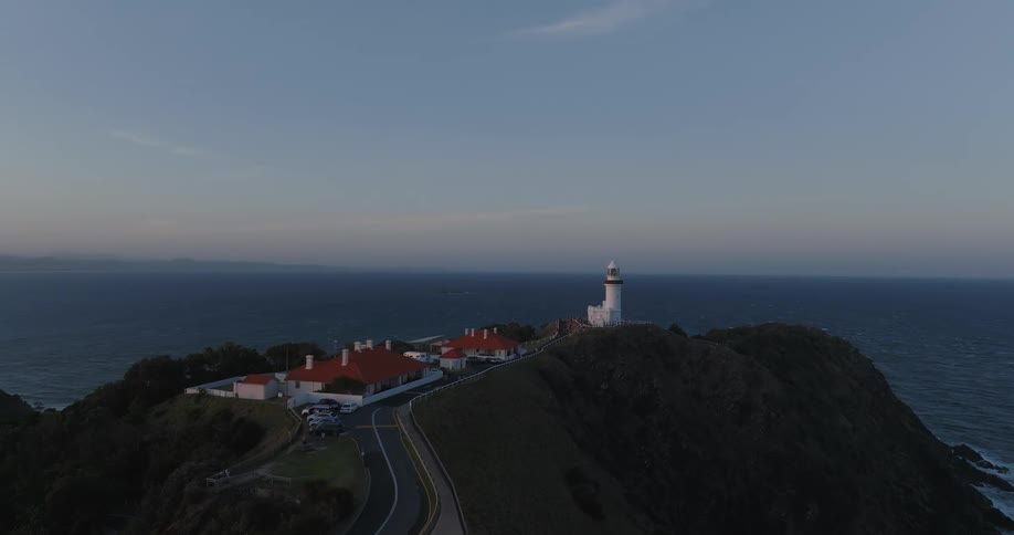 A large house with a road on top of a hill and facing the sea