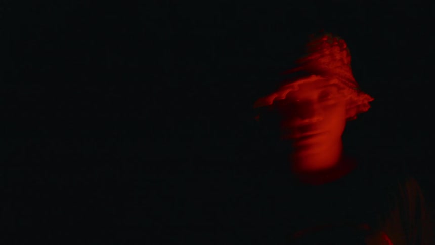A very shaky camera captures the illuminate face of an Asian woman in the dark