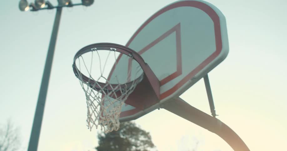 A ball enters a basketball hoop at morning