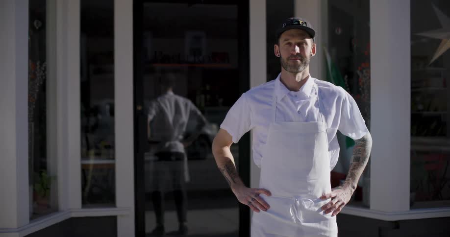 A man in an apron in front of a store