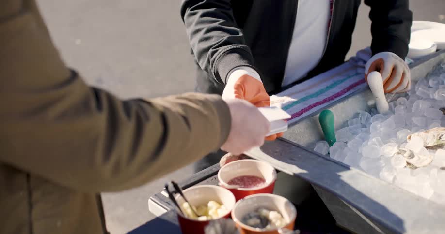 Closeup of the hands of two men with one of them making a payment with a card on a machine