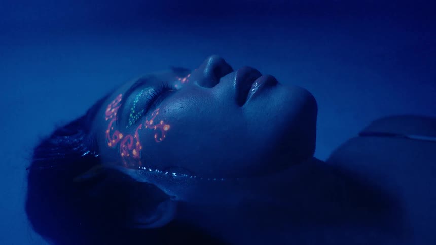 Closeup of an Asian woman's face with bright makeup lying in the water