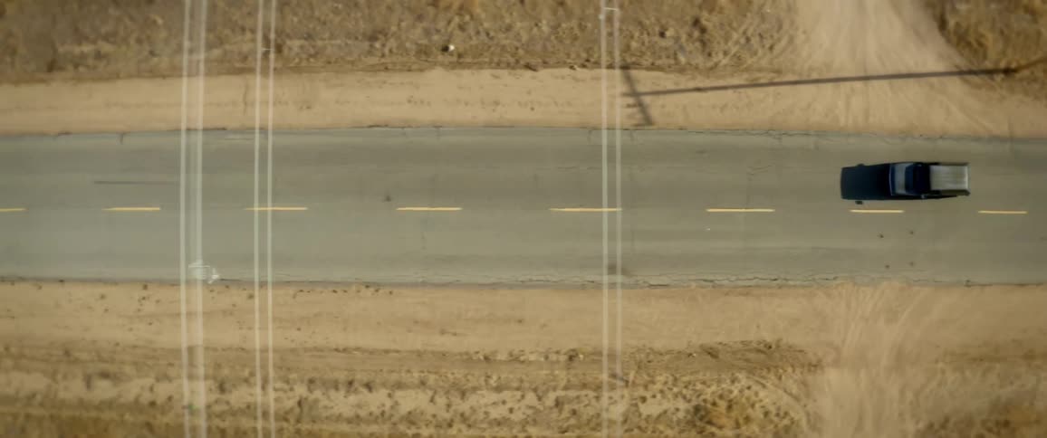 Aerial top down view of a vehicle driving on a road in the desert