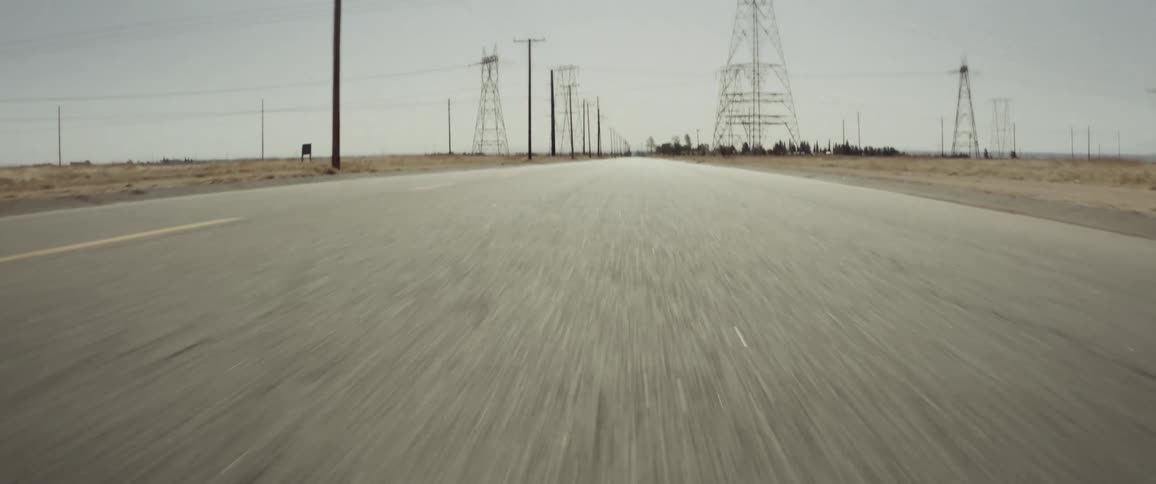 A remote roadway has several large utility towers located along it