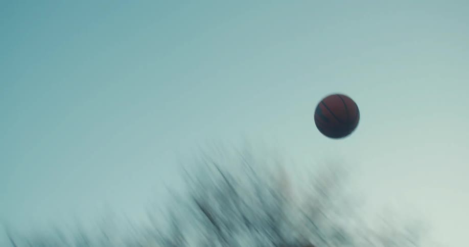 Man scoring a basketball basket on an openair court in the late afternoon