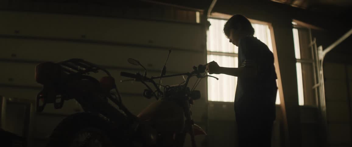 A boy admiring a motorcycle in the garage