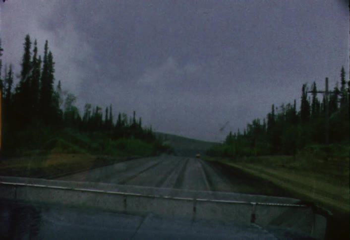 A car is using it windshield wipers as it travels on a rainy day