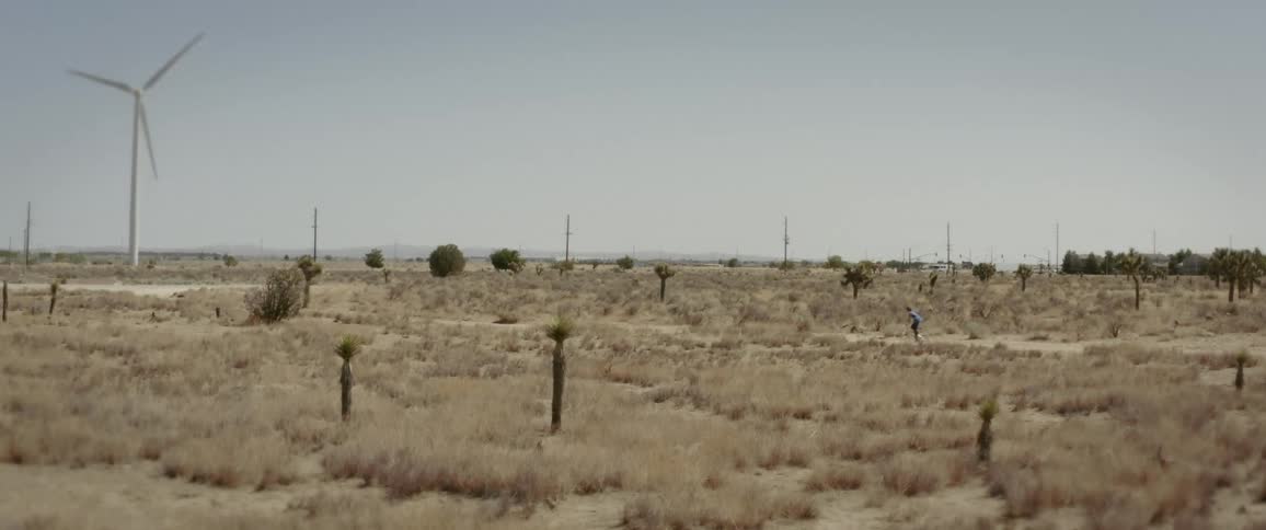A clip of a grass land a windmill and a person riding by