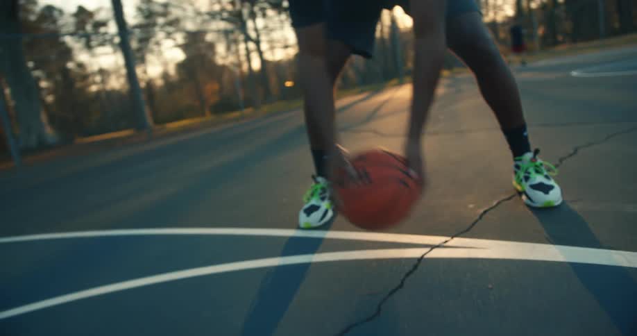 A basketball rolls towards a man ready to play