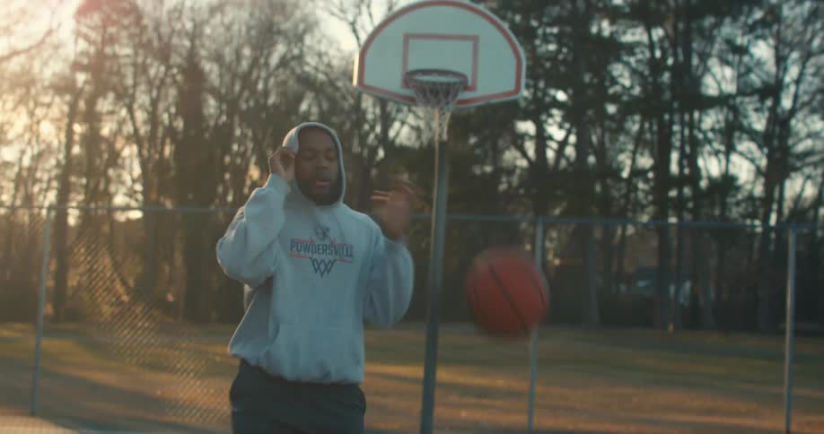 A man playing basketball on a neighborhood court in the morning