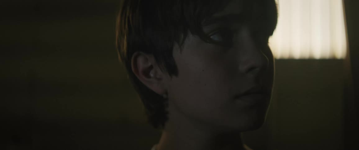 A face of a young boy looking around in a room that is dark