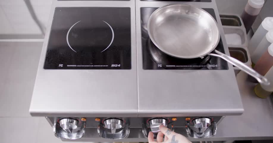 A cook heats up a pan on the stove