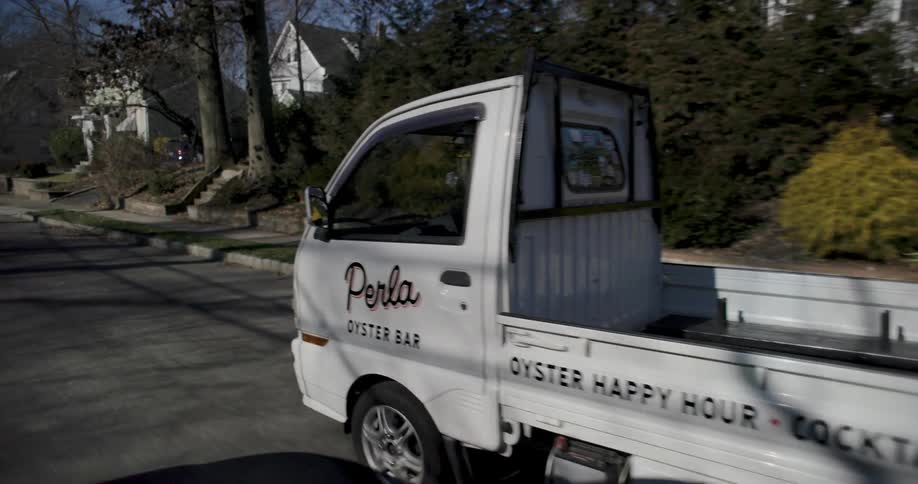A white small catering service truck driving around town