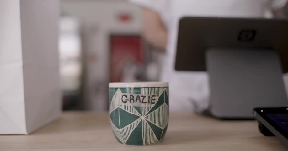 A mug with a written text and a person puts something inside and then takes it out