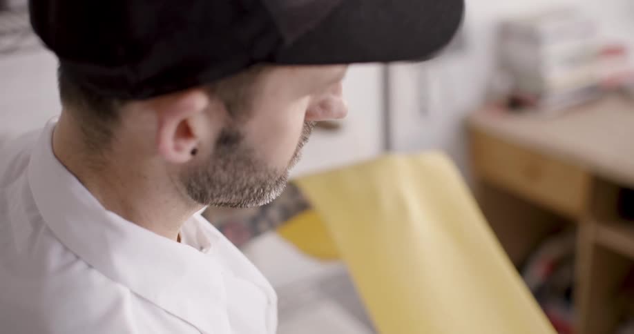 A man in a shop uses a press as he prepares fresh pasta