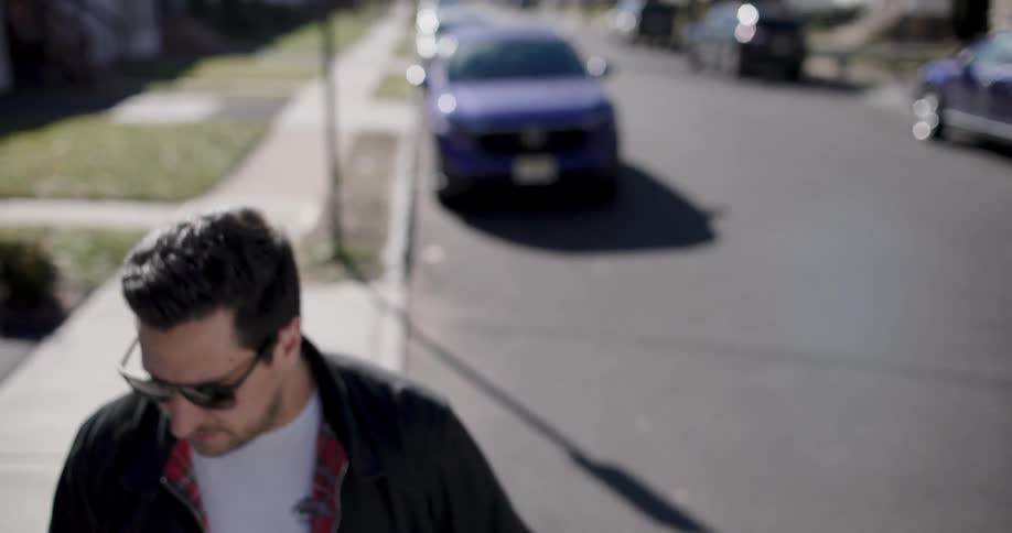 Man nods while standing on sidewalk in residential neighborhood