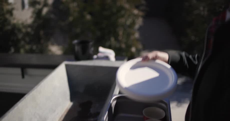 A man wearing sunglasses places a basket with some dishes behind a small truck